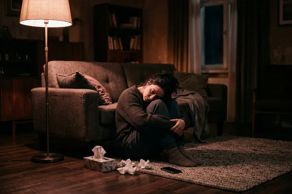 失戀後坐在地板上的女人，燈光昏黃，情緒沉重